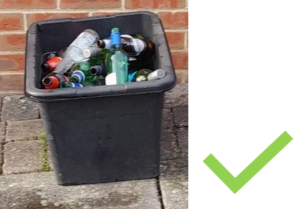 A black plastic glass bin box. Bottles are below the top of the box so it is not overfilled. A green tick is next to the image